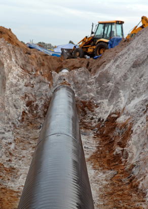 A pipe with a large trench dug around it.