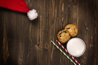 cookies, milk and santa claus hat on a wooden table