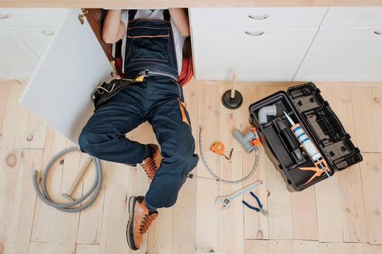 plumber working under sink