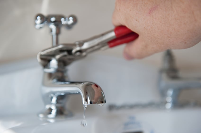 person using a wrench to fix a leaky faucet